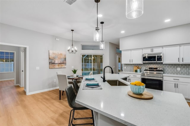 kitchen with white cabinets, appliances with stainless steel finishes, tasteful backsplash, sink, and hanging light fixtures