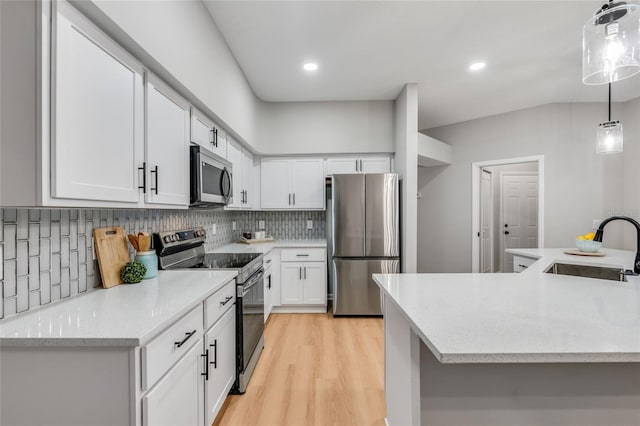 kitchen featuring white cabinetry, stainless steel appliances, decorative backsplash, decorative light fixtures, and sink