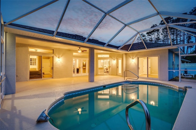 pool at dusk featuring ceiling fan, a lanai, and a patio