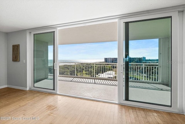 doorway with a textured ceiling and light hardwood / wood-style floors