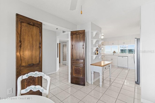 kitchen with ceiling fan, dishwasher, light tile patterned floors, stainless steel fridge, and white cabinets