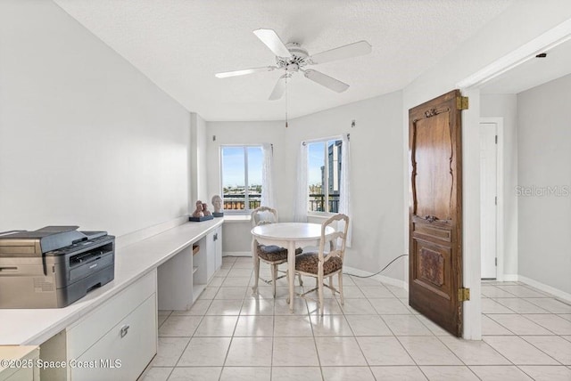 tiled dining area with ceiling fan, built in desk, and a textured ceiling