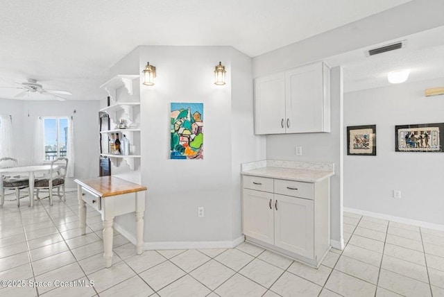 kitchen featuring white cabinetry, ceiling fan, light tile patterned flooring, and a textured ceiling