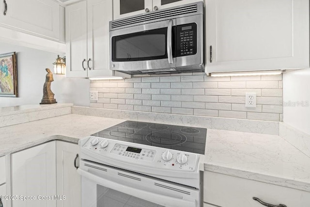 kitchen with light stone countertops, white cabinetry, tasteful backsplash, and white electric range oven