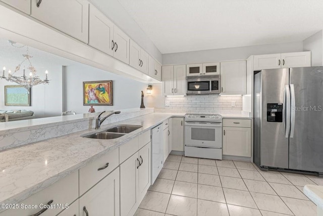 kitchen with appliances with stainless steel finishes, tasteful backsplash, sink, a notable chandelier, and white cabinetry