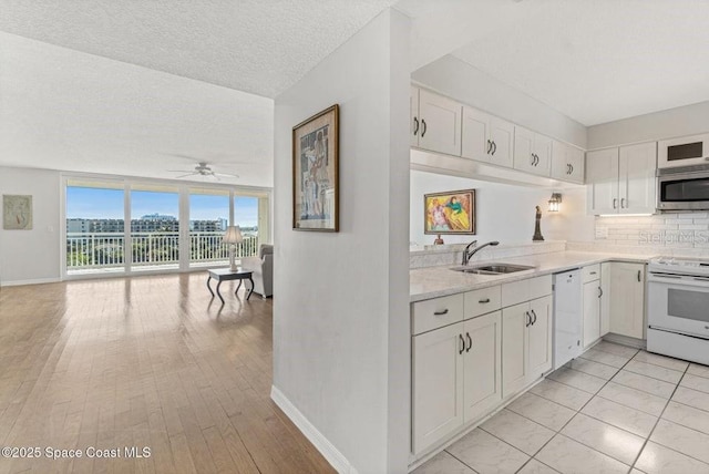 kitchen with tasteful backsplash, white appliances, ceiling fan, sink, and white cabinetry