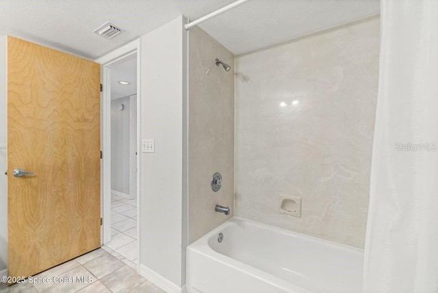 bathroom with tile patterned floors, shower / bath combination with curtain, and a textured ceiling