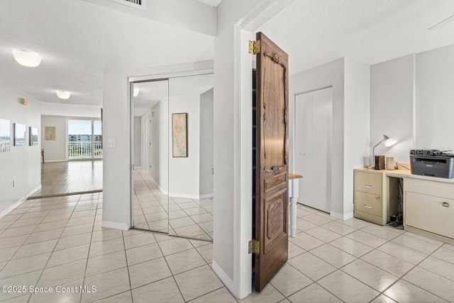 corridor featuring light tile patterned floors and a textured ceiling