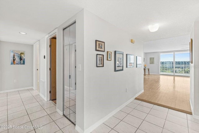 corridor with light tile patterned floors and a textured ceiling