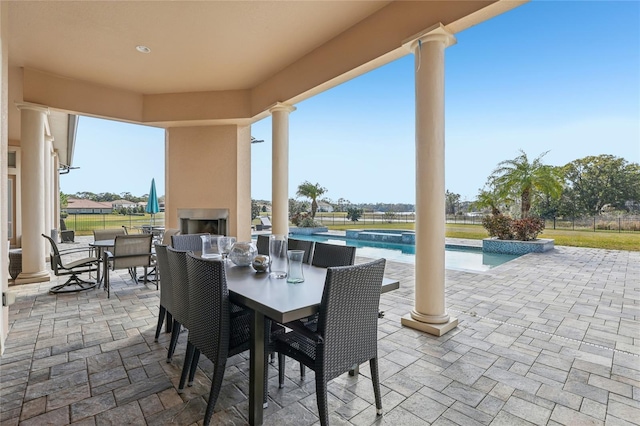 view of patio / terrace featuring a large fireplace, a pool with connected hot tub, and outdoor dining space