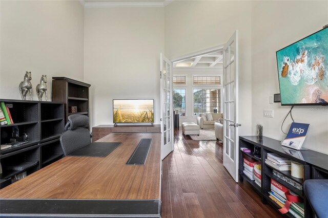 office space featuring coffered ceiling, a towering ceiling, french doors, ornamental molding, and dark wood-style floors