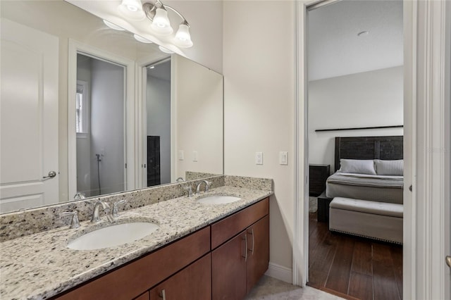 bathroom featuring double vanity, wood finished floors, a sink, and baseboards