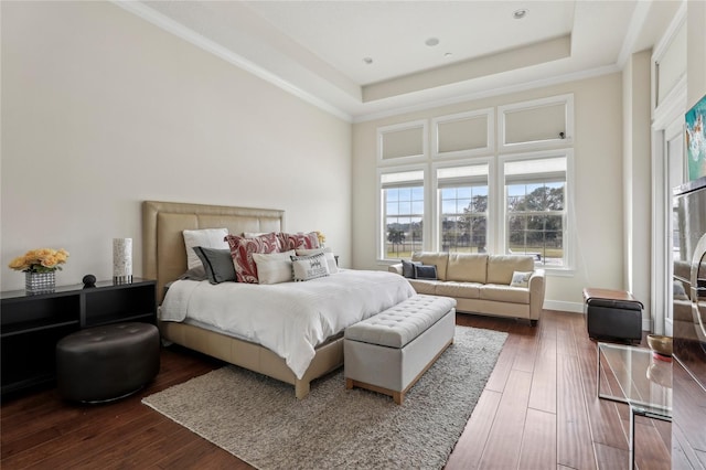 bedroom with ornamental molding, a raised ceiling, dark wood finished floors, and baseboards