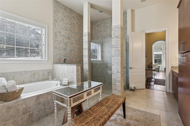 bathroom featuring vanity, walk in shower, a bath, and tile patterned floors