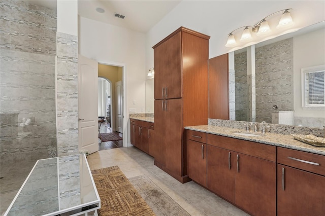 full bath featuring visible vents, a sink, tile patterned flooring, a walk in shower, and two vanities