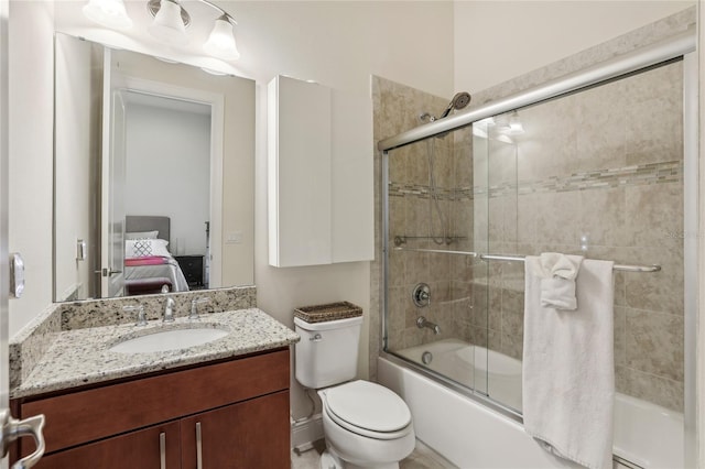 full bathroom with ensuite bathroom, bath / shower combo with glass door, vanity, and toilet