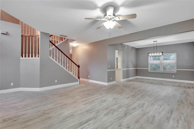 spare room featuring ceiling fan with notable chandelier and light hardwood / wood-style floors