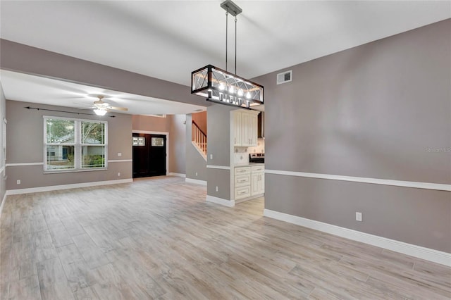 unfurnished living room with light hardwood / wood-style flooring and ceiling fan with notable chandelier