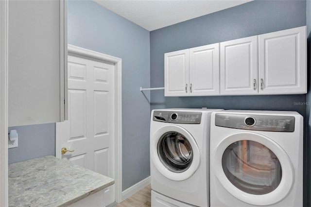 laundry room with washer and dryer, cabinets, and light wood-type flooring