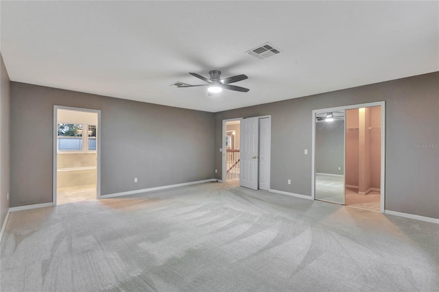 unfurnished bedroom featuring light colored carpet, ceiling fan, and connected bathroom