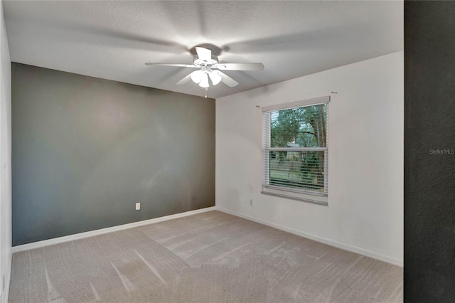 unfurnished room featuring ceiling fan, light colored carpet, and a textured ceiling