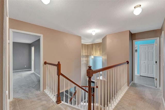 corridor with a textured ceiling and light carpet