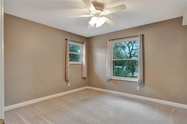 empty room with carpet flooring, ceiling fan, and a wealth of natural light