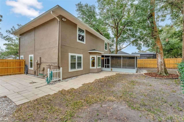 rear view of house featuring a sunroom and a patio area