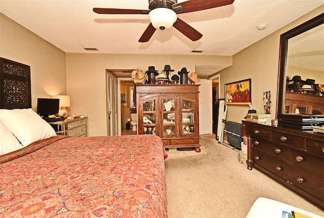 bedroom with ceiling fan, light carpet, and a textured ceiling