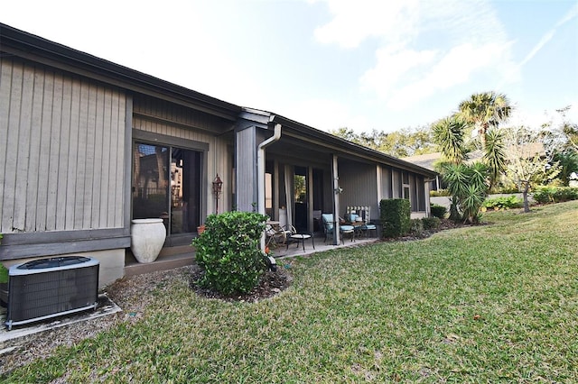 rear view of property featuring a yard, central AC unit, and a patio