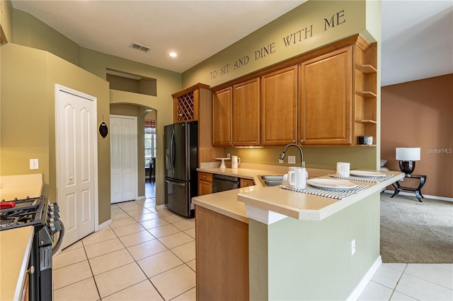 kitchen with black appliances, light tile patterned flooring, kitchen peninsula, and sink