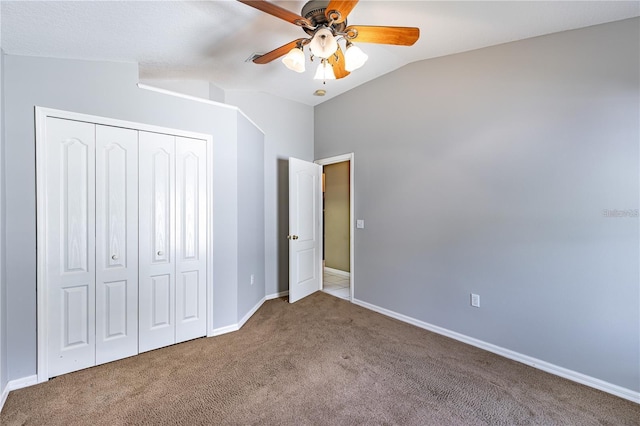 unfurnished bedroom featuring carpet, a closet, ceiling fan, and lofted ceiling