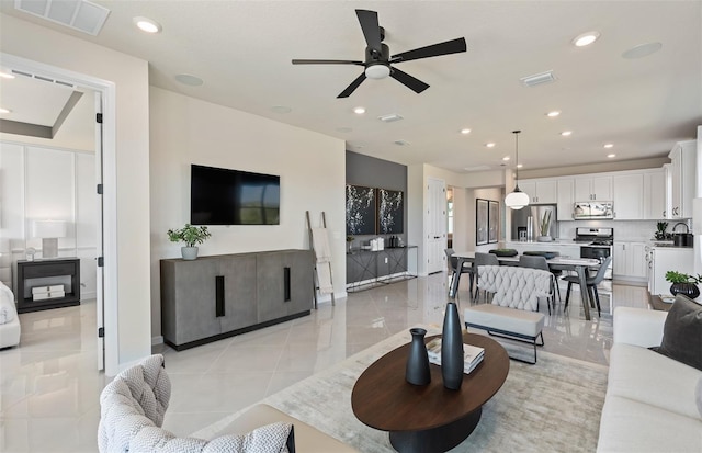 living room featuring ceiling fan, light tile patterned flooring, and sink