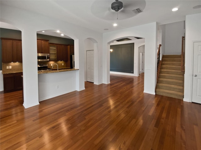 unfurnished living room featuring ceiling fan and dark wood-type flooring