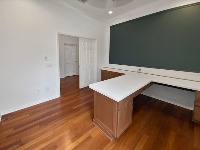 unfurnished office with built in desk and hardwood / wood-style floors