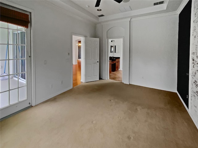 carpeted empty room featuring ornamental molding, ceiling fan, a tray ceiling, and a wealth of natural light