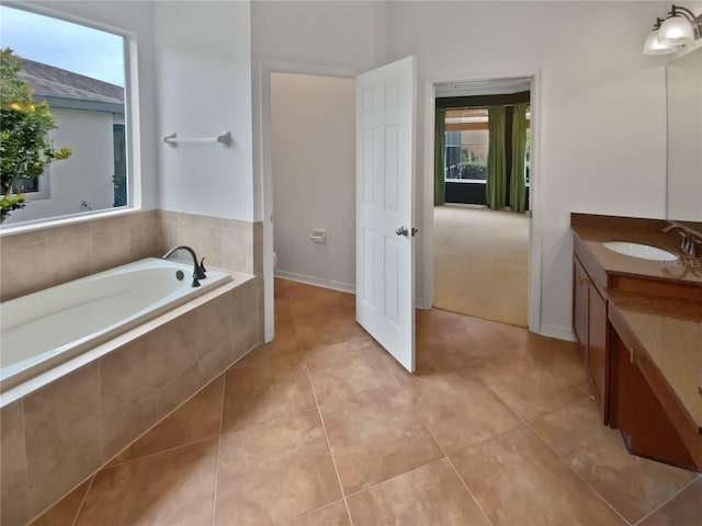 bathroom with tiled bath, tile patterned floors, a wealth of natural light, and vanity