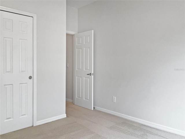 unfurnished bedroom featuring light colored carpet and a closet