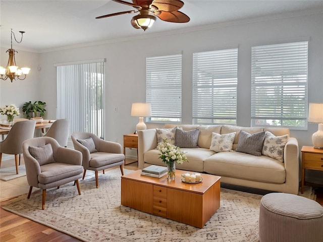 living room featuring ornamental molding, light wood-type flooring, and ceiling fan with notable chandelier