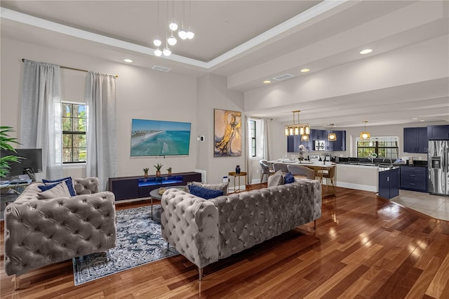 living room featuring dark hardwood / wood-style floors, plenty of natural light, a chandelier, and a tray ceiling