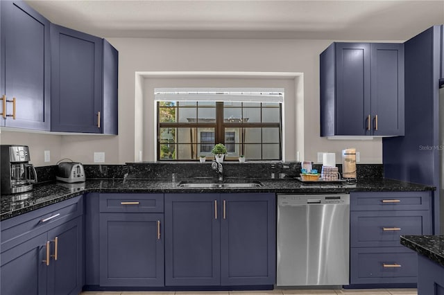 kitchen with blue cabinetry, stainless steel dishwasher, dark stone countertops, and sink