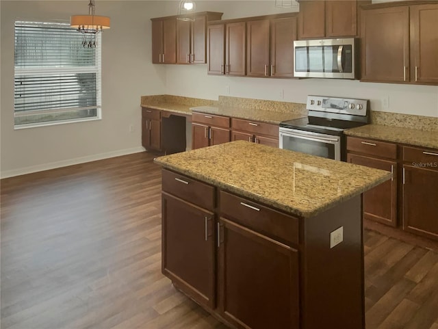 kitchen featuring stainless steel appliances, a center island, light stone counters, dark hardwood / wood-style flooring, and pendant lighting