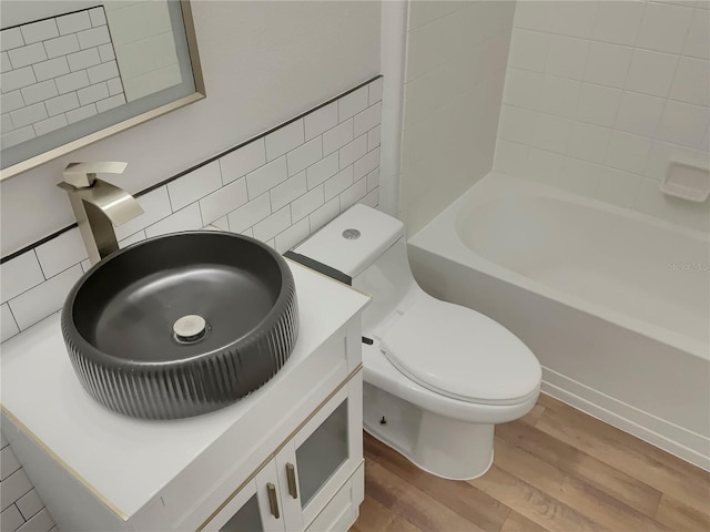 full bathroom featuring hardwood / wood-style floors, toilet, vanity, shower / bathing tub combination, and backsplash