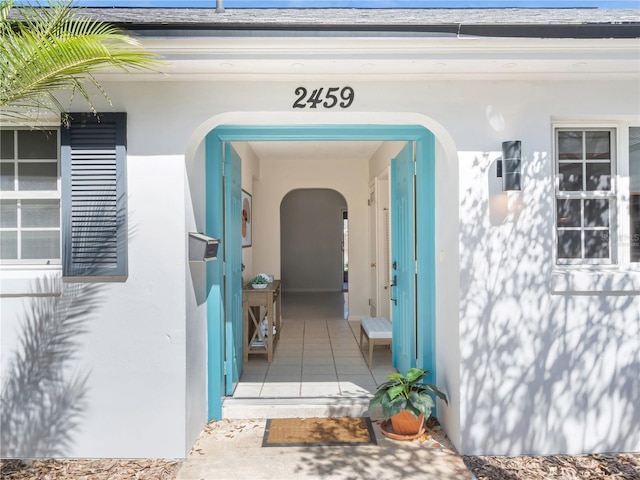 property entrance featuring a shingled roof and stucco siding