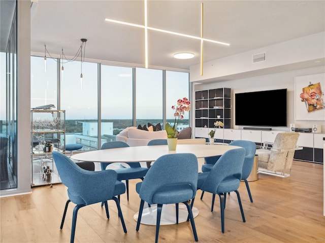 dining space featuring light wood-type flooring and a wall of windows