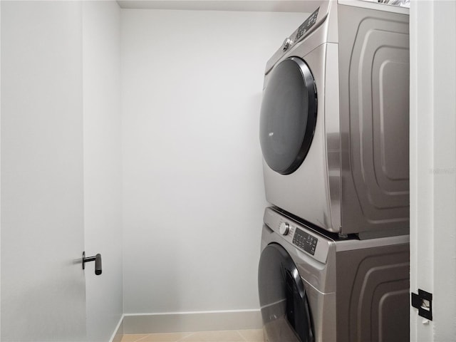 laundry area with light tile patterned floors and stacked washer / dryer