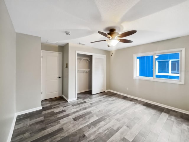 unfurnished bedroom with a textured ceiling, ceiling fan, a closet, and hardwood / wood-style floors