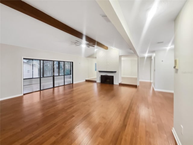 unfurnished living room featuring ceiling fan, hardwood / wood-style flooring, and beam ceiling