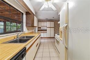 kitchen with white refrigerator with ice dispenser, dishwasher, light tile patterned floors, white cabinets, and sink