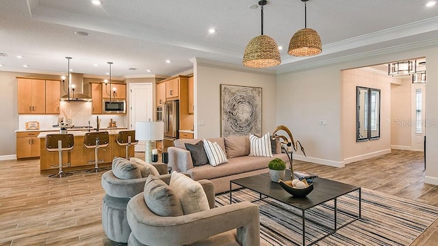 living room with a tray ceiling, crown molding, and light wood-type flooring